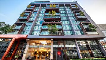 Un hotel moderno con varios pisos, amplias ventanas y zonas de estar al aire libre.