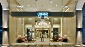 A modern hotel lobby with a chandelier, seating area, and a reception desk.