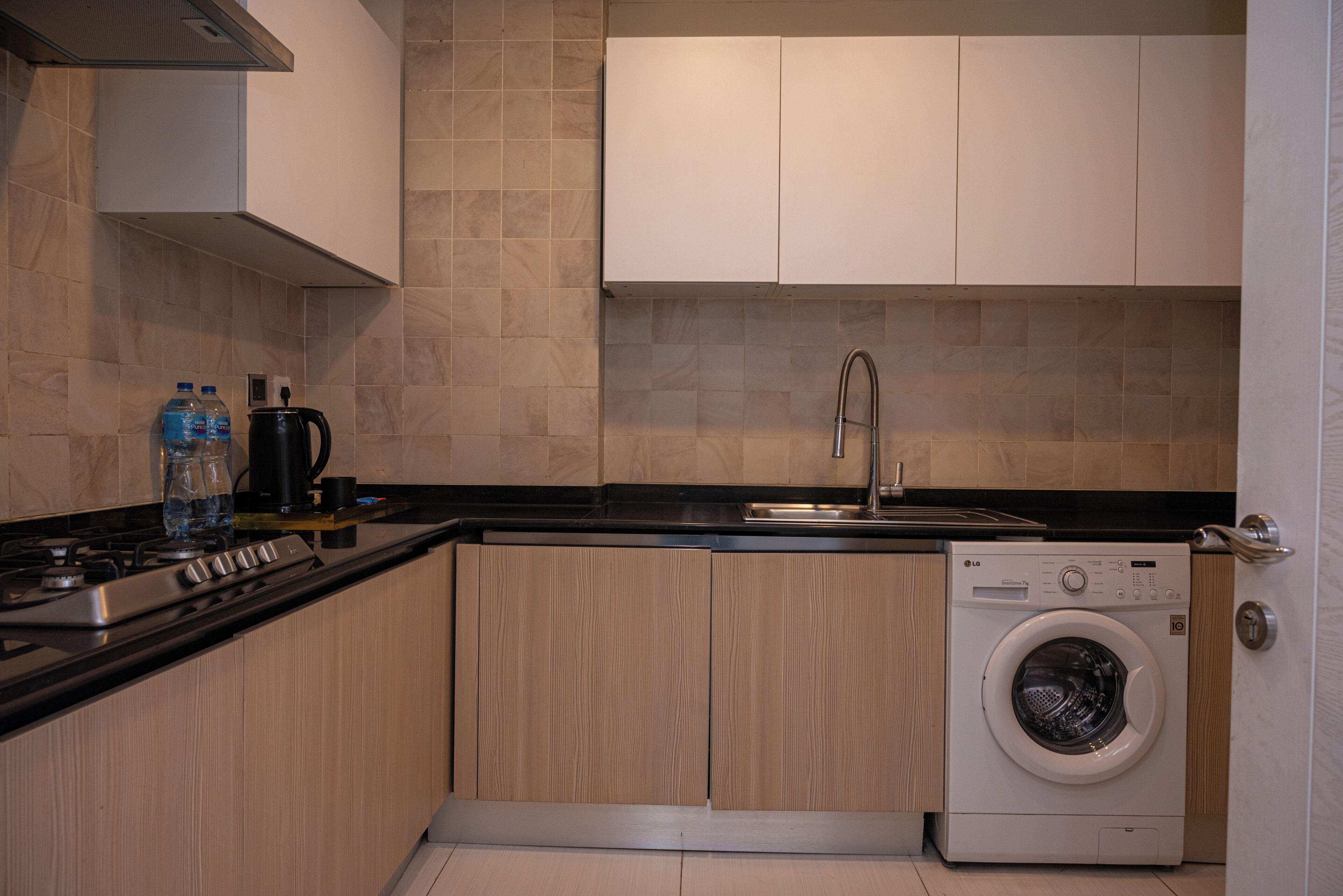 Cocina compacta con estufa, lavamanos y lavadora.