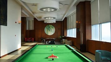 Una mesa de billar con bolas y un ventanal con persianas.