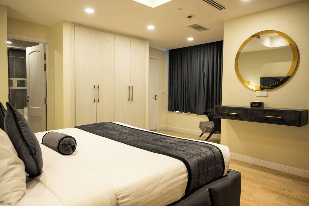 Un dormitorio moderno con una cama, un aparador, un espejo y una ventana con cortinas.