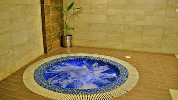 Relax in a serene spa area with a hot tub surrounded by a mosaic tile border and a patterned floor.