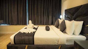 Una cama con cabecera oscura, ropa de cama blanca y una toalla al lado.
