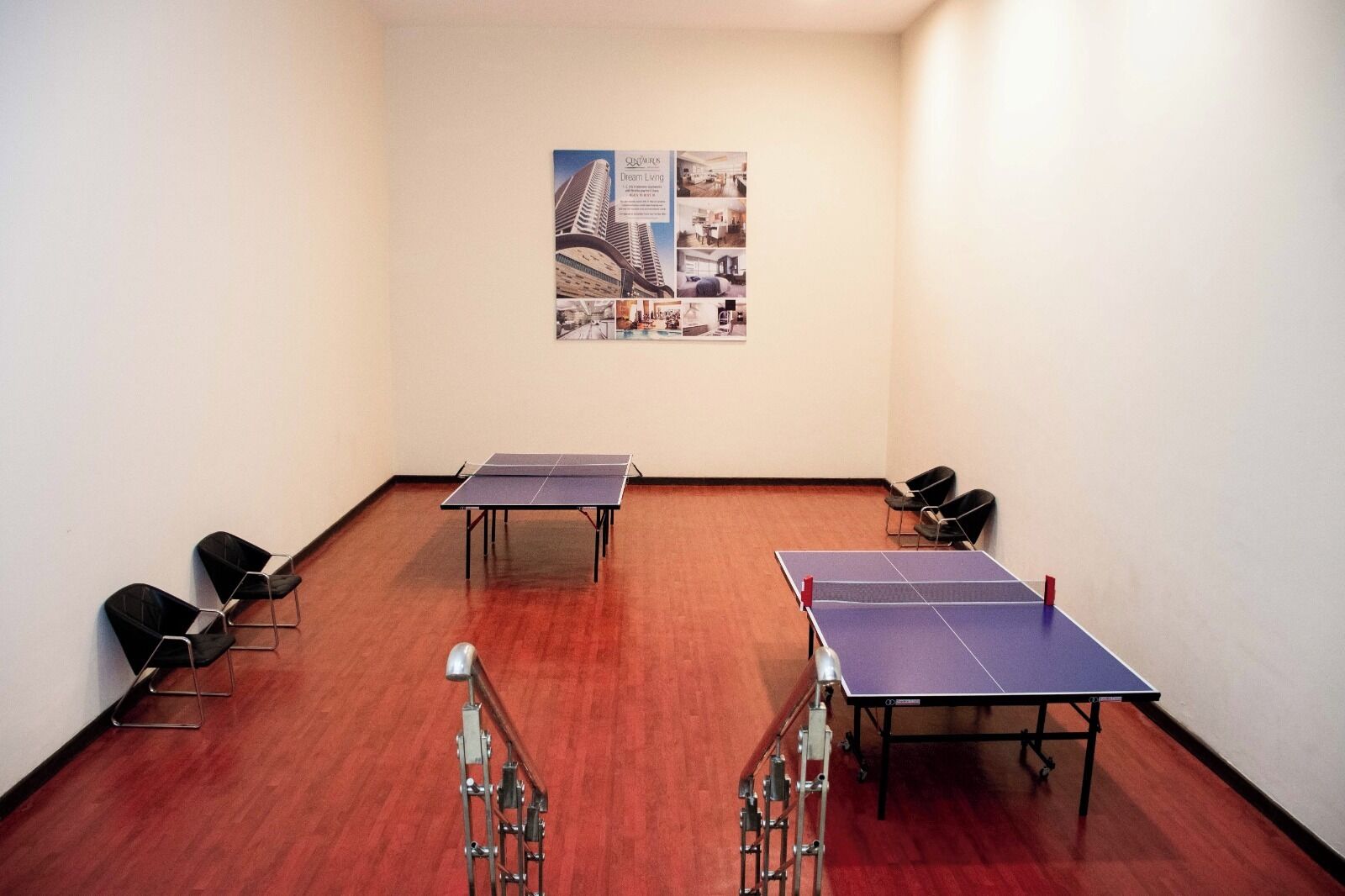 A room with two ping pong tables, chairs, and a poster on the wall.