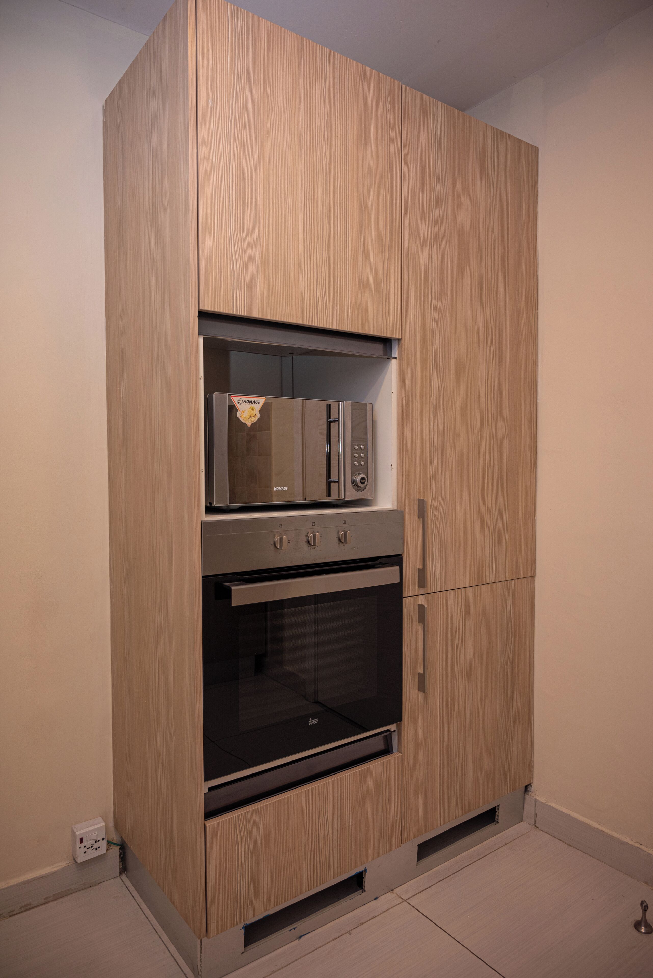 A built-in kitchen with a microwave, oven, and cabinet doors.