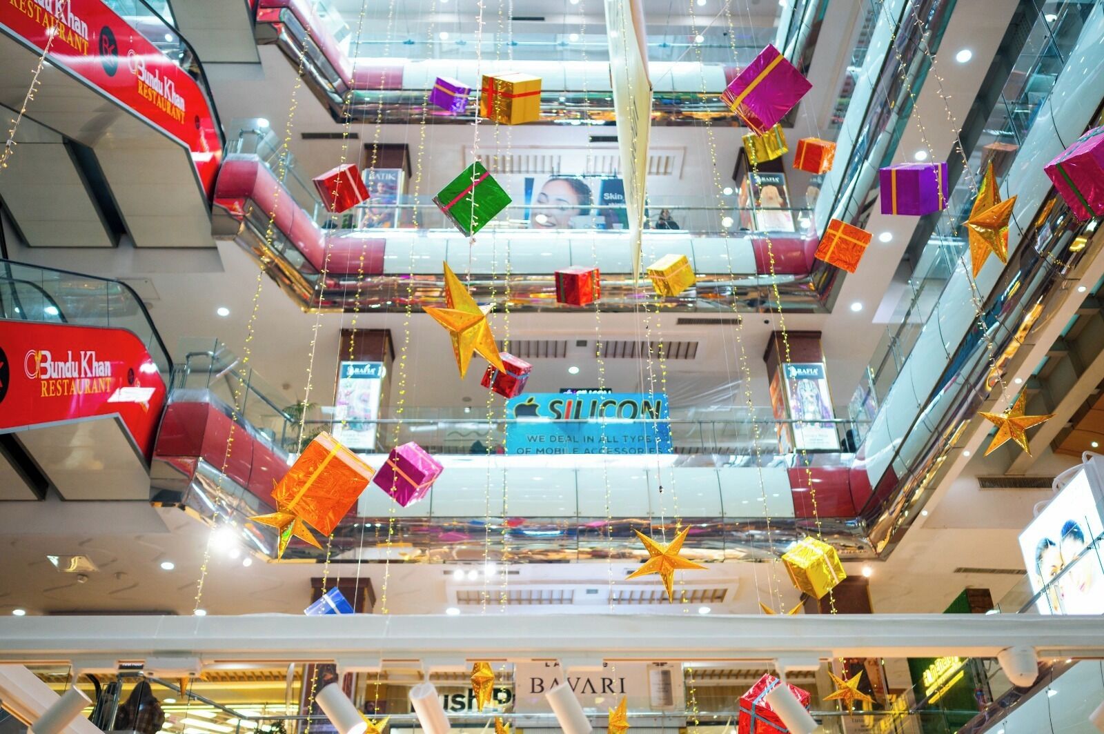 A multi-level shopping mall with various stores, including a visible restaurant sign and a prominent electronics store.