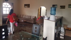 Un salon comprenant un canapé, une table basse en verre, un distributeur d’eau et un ventilateur de plafond.