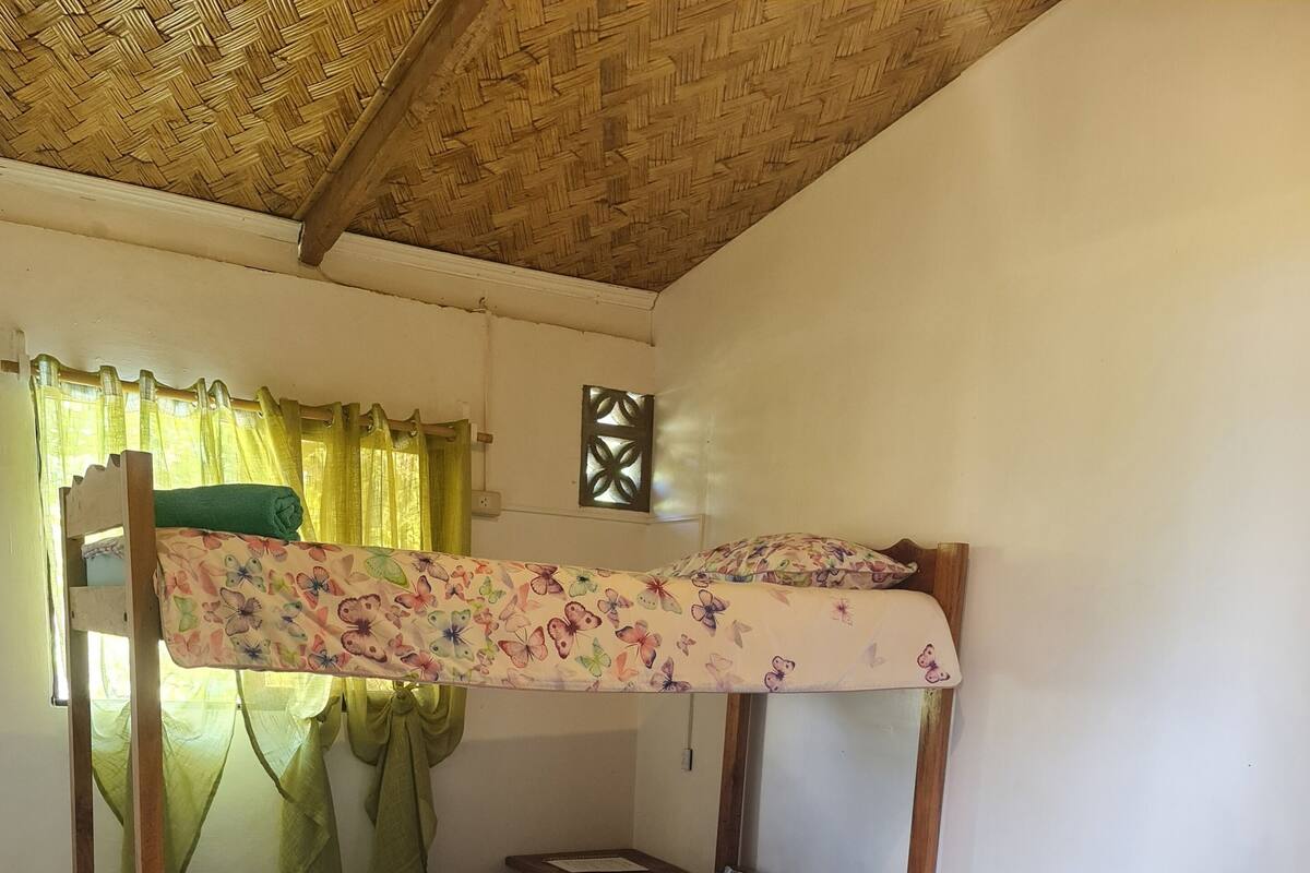 A bunk bed with floral bedding, a wooden chair, and a tiled floor.