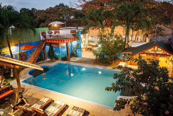 Una piscina al aire libre, sombrillas, sillones reclinables de piscina