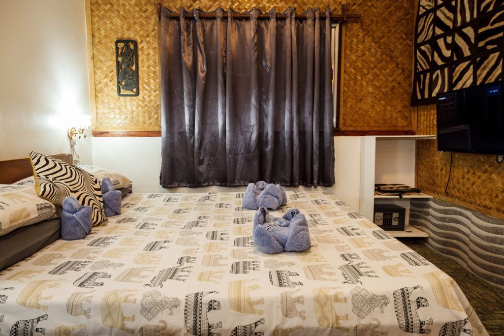 A hotel room with a bed, a television, and a wall-mounted TV.