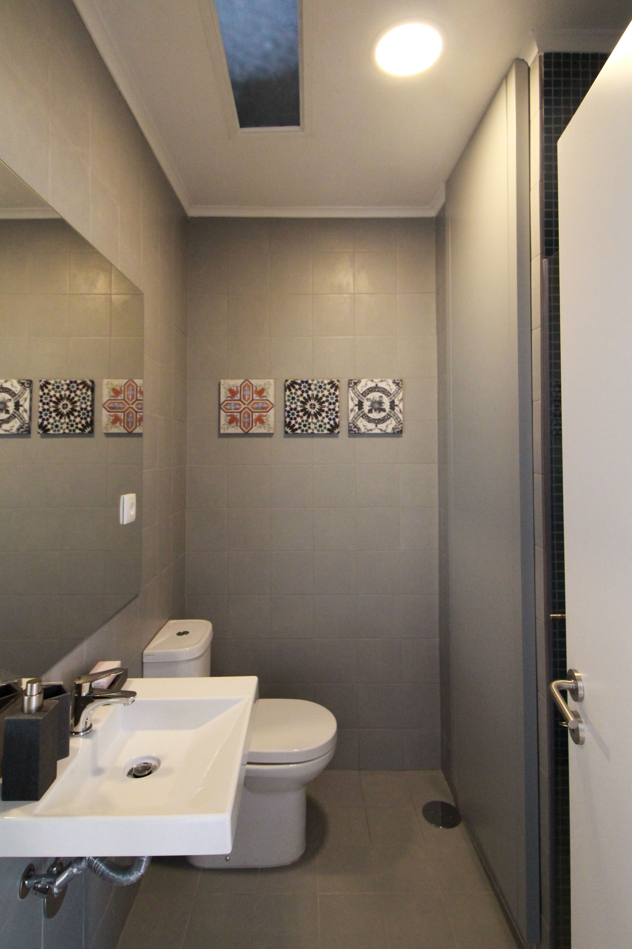 A modern bathroom with a white sink, toilet, and shower.