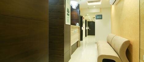 A modern hotel lobby with a wooden reception desk, a bench, and a wall-mounted air conditioning unit.