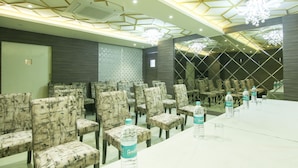A conference room with rows of chairs, a long table, and water bottles on the table. - Treebo Hoops - Airport, VIP Road (Barasat)