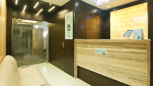 A reception area with a marble reception desk, a glass door entrance, and a modern chandelier. - Treebo Hoops - Airport, VIP Road (Barasat)