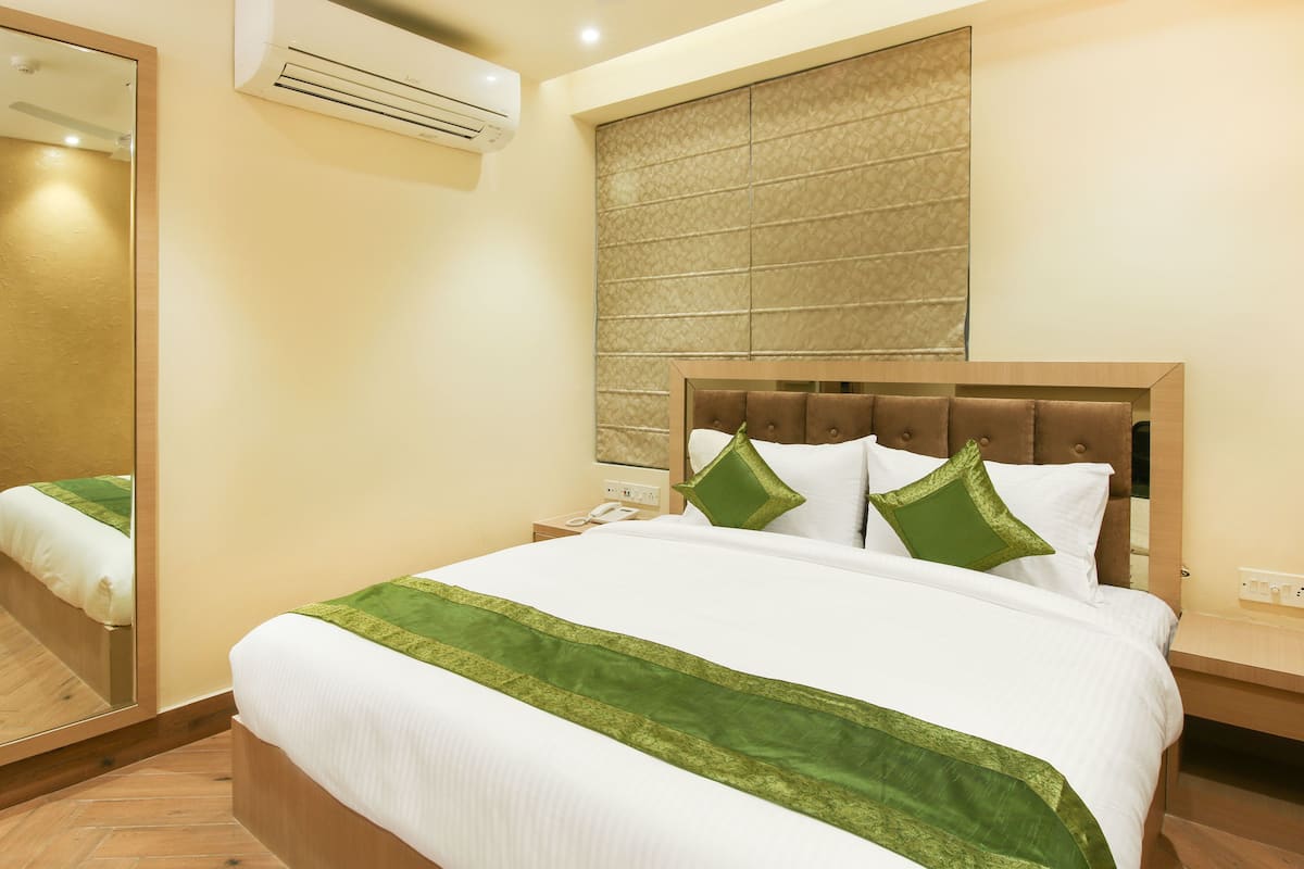 Habitación de hotel con una cama grande, una mesita de noche con teléfono y aire acondicionado de pared.