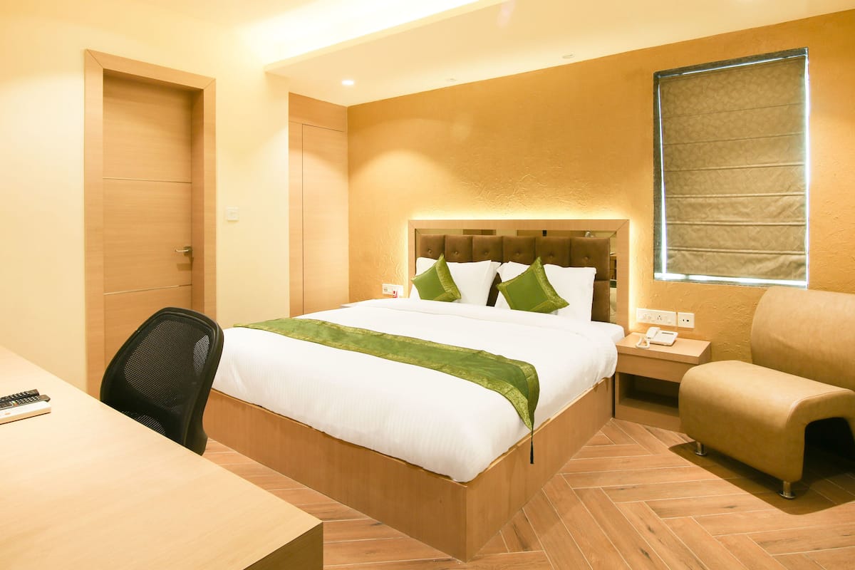 Una habitación de hotel con cama, escritorio, silla y ventana.