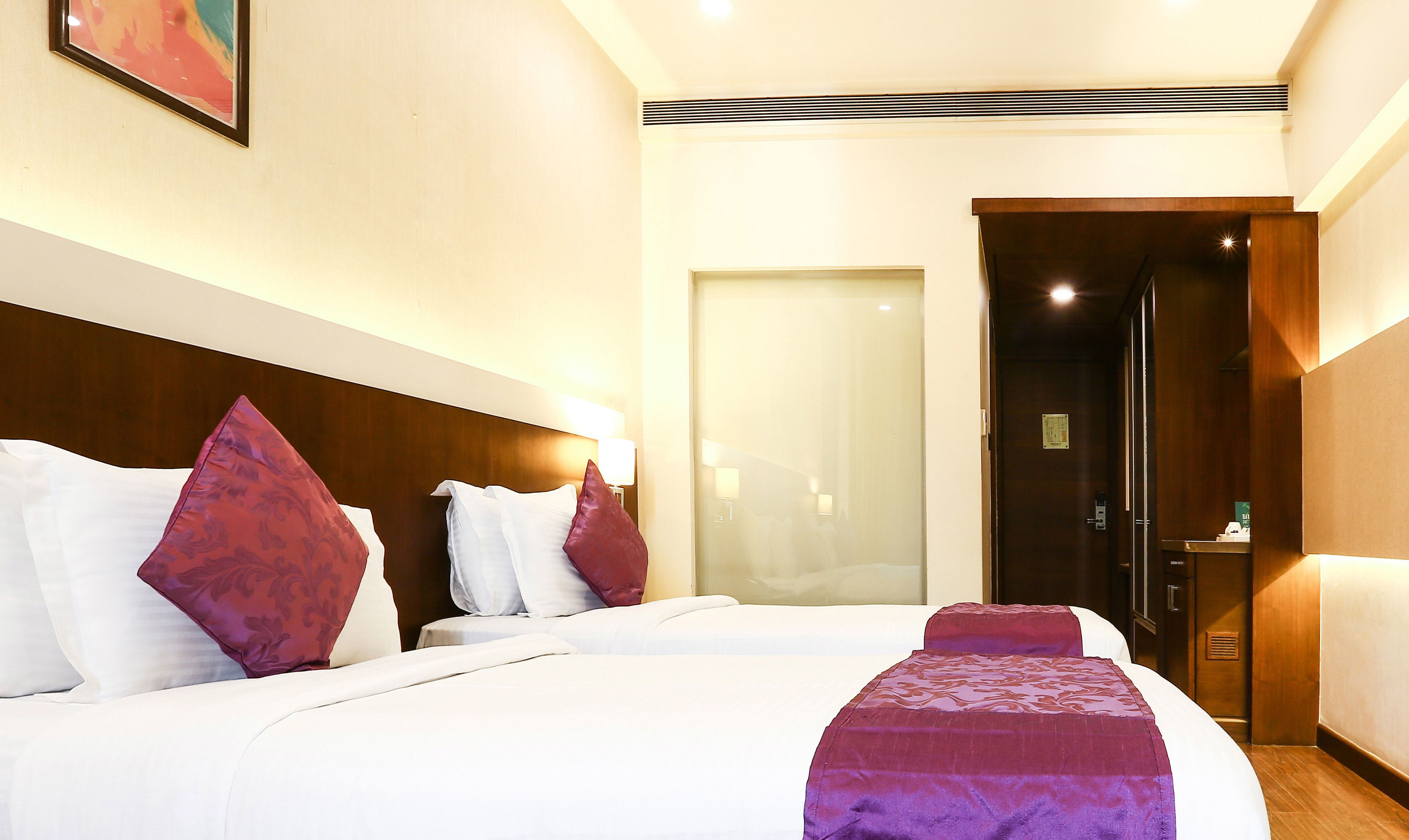 A hotel room with a large bed, two bedside tables, a nightstand, and a door leading to a bathroom.