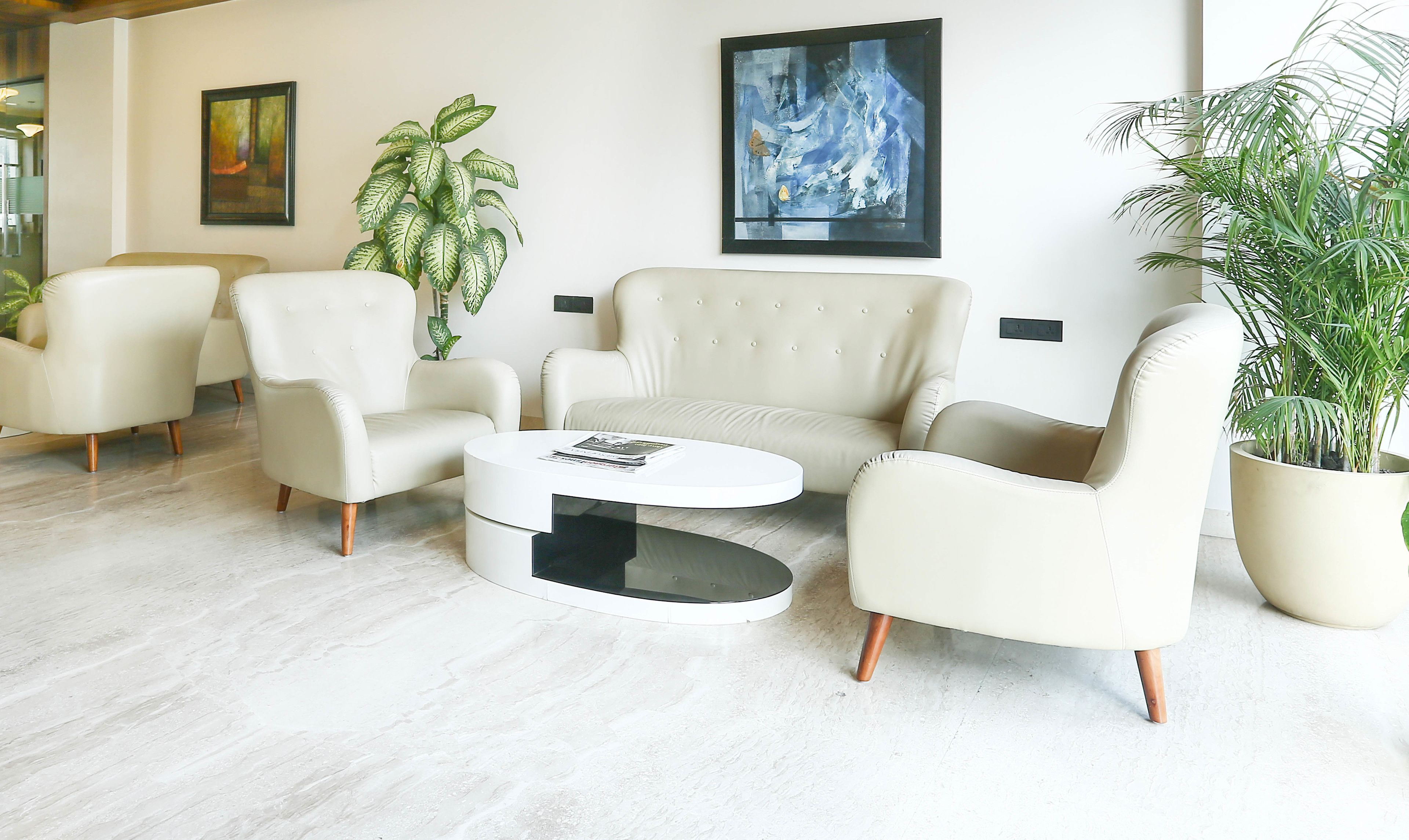 Un espace de détente moderne avec des fauteuils en cuir, une table basse ronde et des plantes en pot.