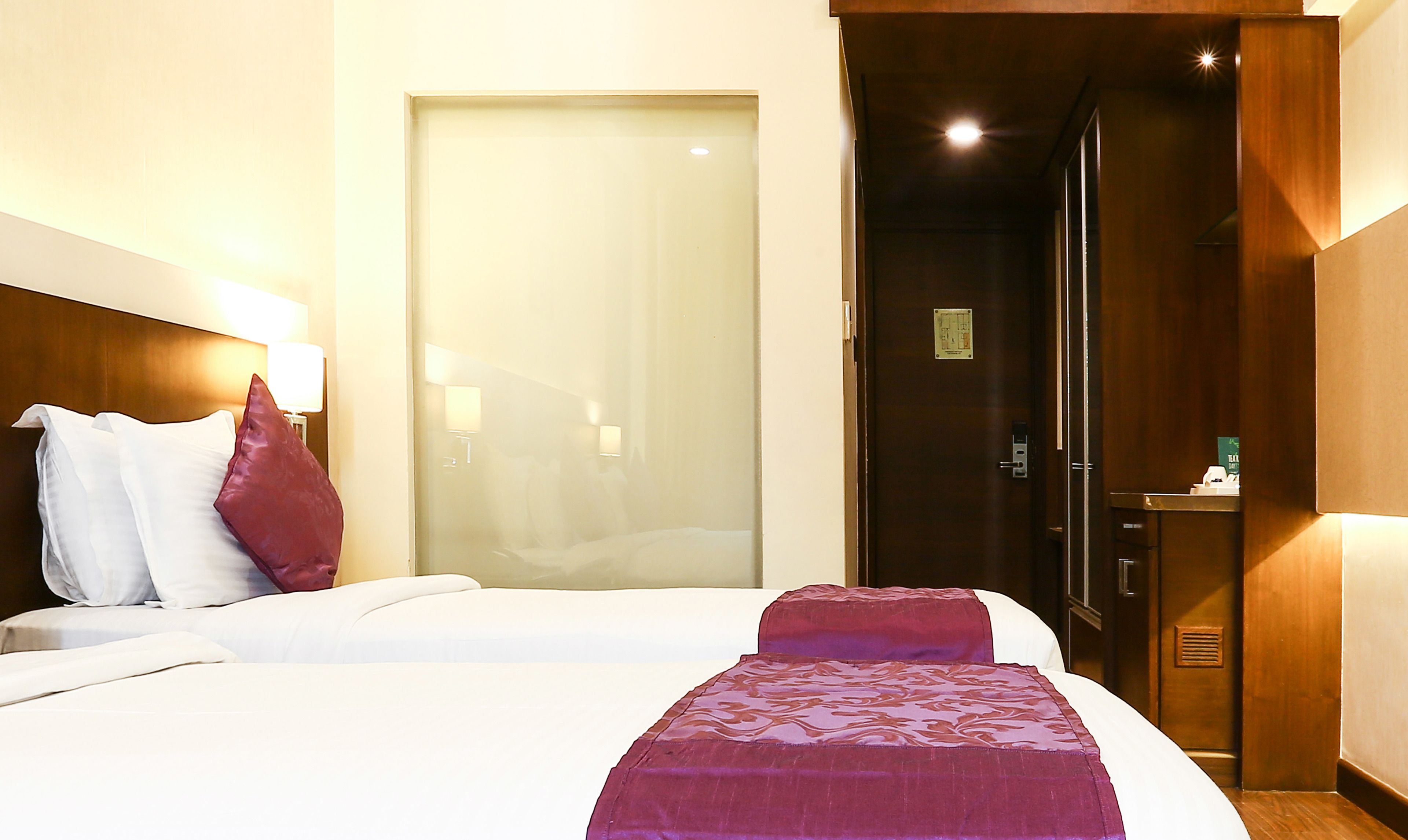 Une chambre d’hôtel avec un lit, des oreillers, une table de chevet, une porte et un miroir.