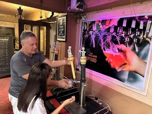 A bar area with a tap labeled 'The Palms' and a poster of hands holding a glass. - 1st Street Park Apartelle (Angeles City)
