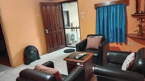 A living room with a sofa set, a coffee table, and a fan. - 1st Street Park Apartelle (Angeles City)