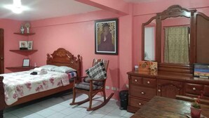 A bedroom with a bed, a rocking chair, a dresser, and a mirror. - 1st Street Park Apartelle (Angeles City)