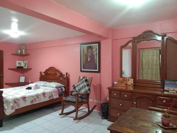 Ein Schlafzimmer mit einem Bett, einem Schaukelstuhl, einem Schminktisch und einem Spiegel.