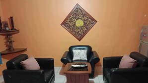 A living room with two black leather sofas, a wooden coffee table, and a decorative wall hanging. - 1st Street Park Apartelle (Angeles City)
