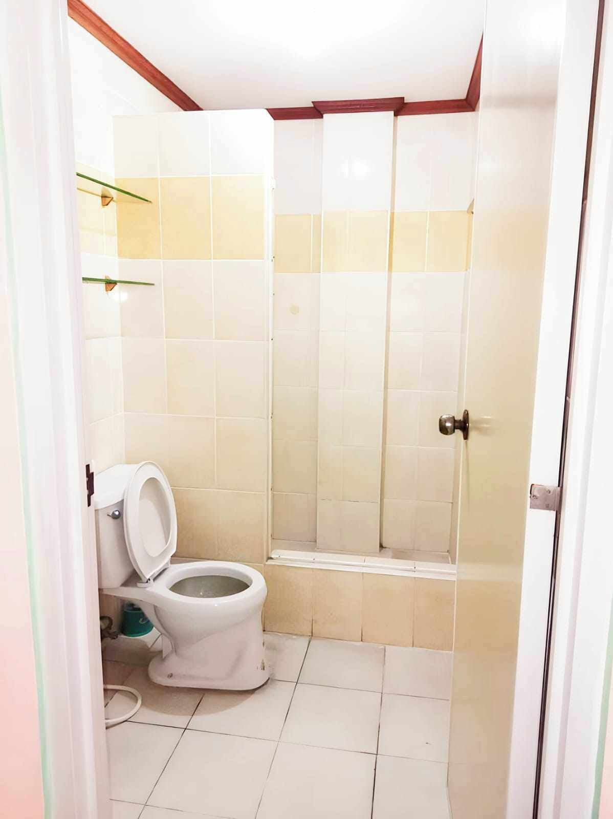 A bathroom with a toilet, a shower, and tiled walls.