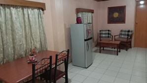 A compact living space with a dining table, chairs, a refrigerator, and a small seating area with two chairs. - 1st Street Park Apartelle (Angeles City)