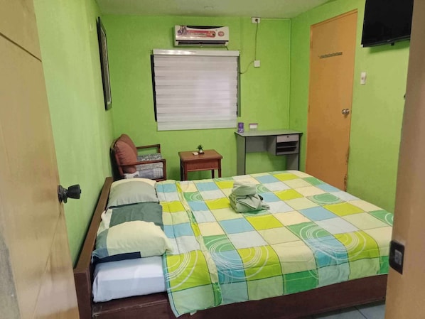 A small, green-walled bedroom with a bed, a chair, a desk, and a window. - 1st Street Park Apartelle (Angeles City)