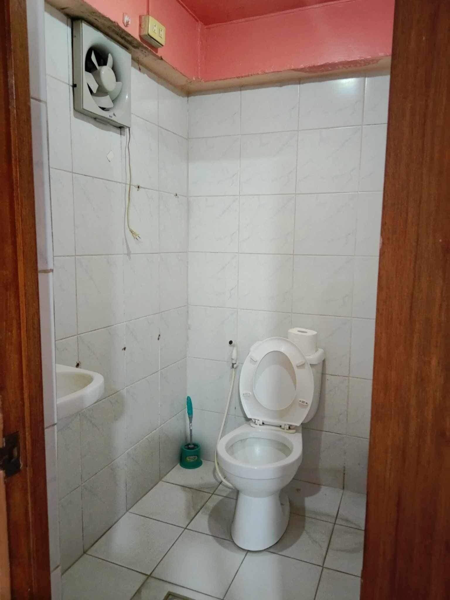 Un baño pequeño con inodoro, lavamanos y ventilador.