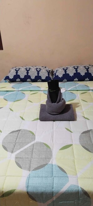 Un lit avec une couvre-lit à motifs et des oreillers aux couleurs bleu et blanc.
