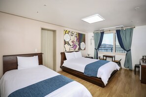 Una camera d'albergo con due letti, una scrivania, una sedia, una finestra con tende e un quadro appeso al muro.
