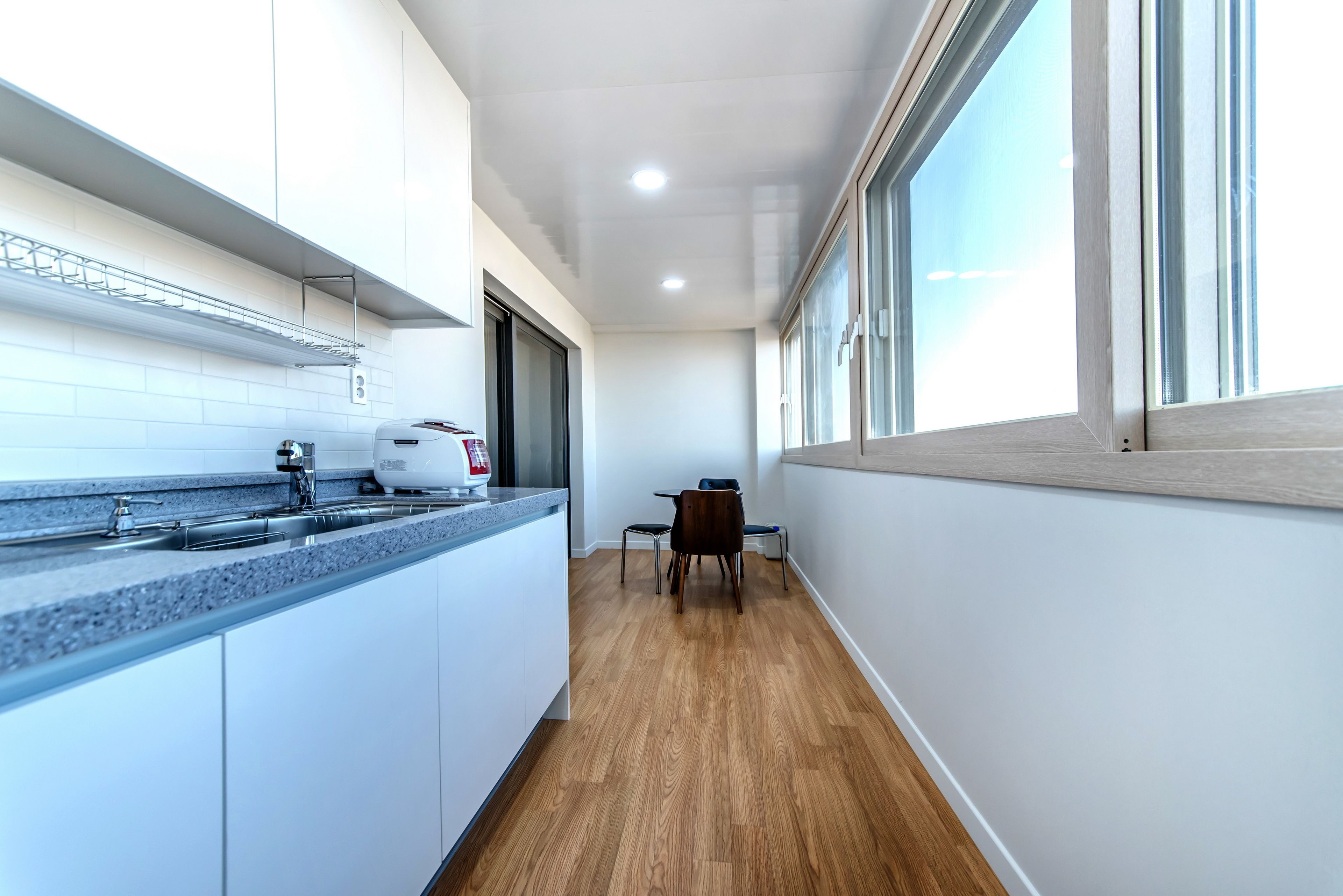 A modern kitchen with white cabinets, a granite countertop, and a built-in oven. There is a dining area with a table and chairs, and a window providing natural light.