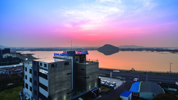 Un hotel dal design moderno, situato vicino all'acqua con un tramonto sullo sfondo.