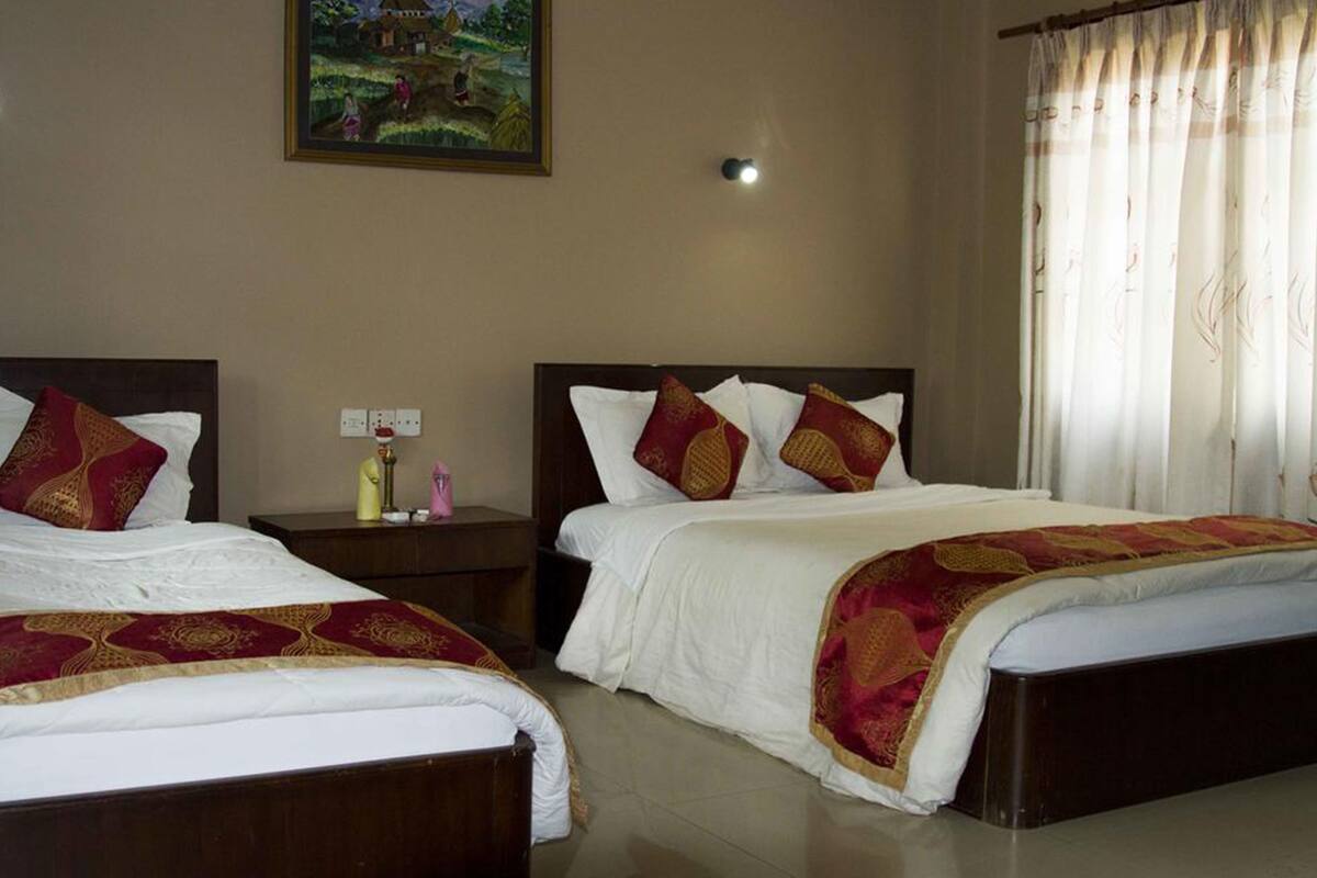 A hotel room with two beds, a nightstand, a lamp, and a painting on the wall.