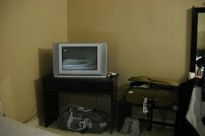 A television on a stand, a suitcase, and a bag on the floor. - Hotel Parkland (Sauraha)
