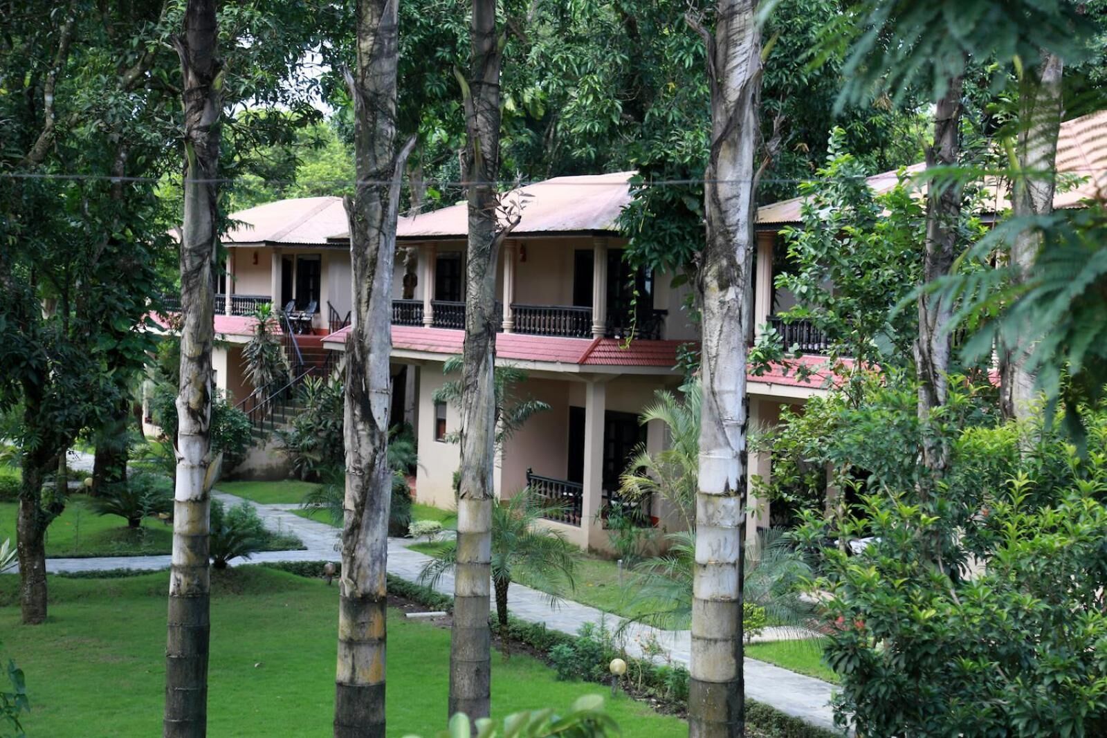 A multi-story building with balconies, surrounded by lush greenery and palm trees.