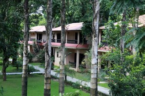 A multi-story building with balconies, surrounded by lush greenery and palm trees. - Hotel Parkland (Sauraha)