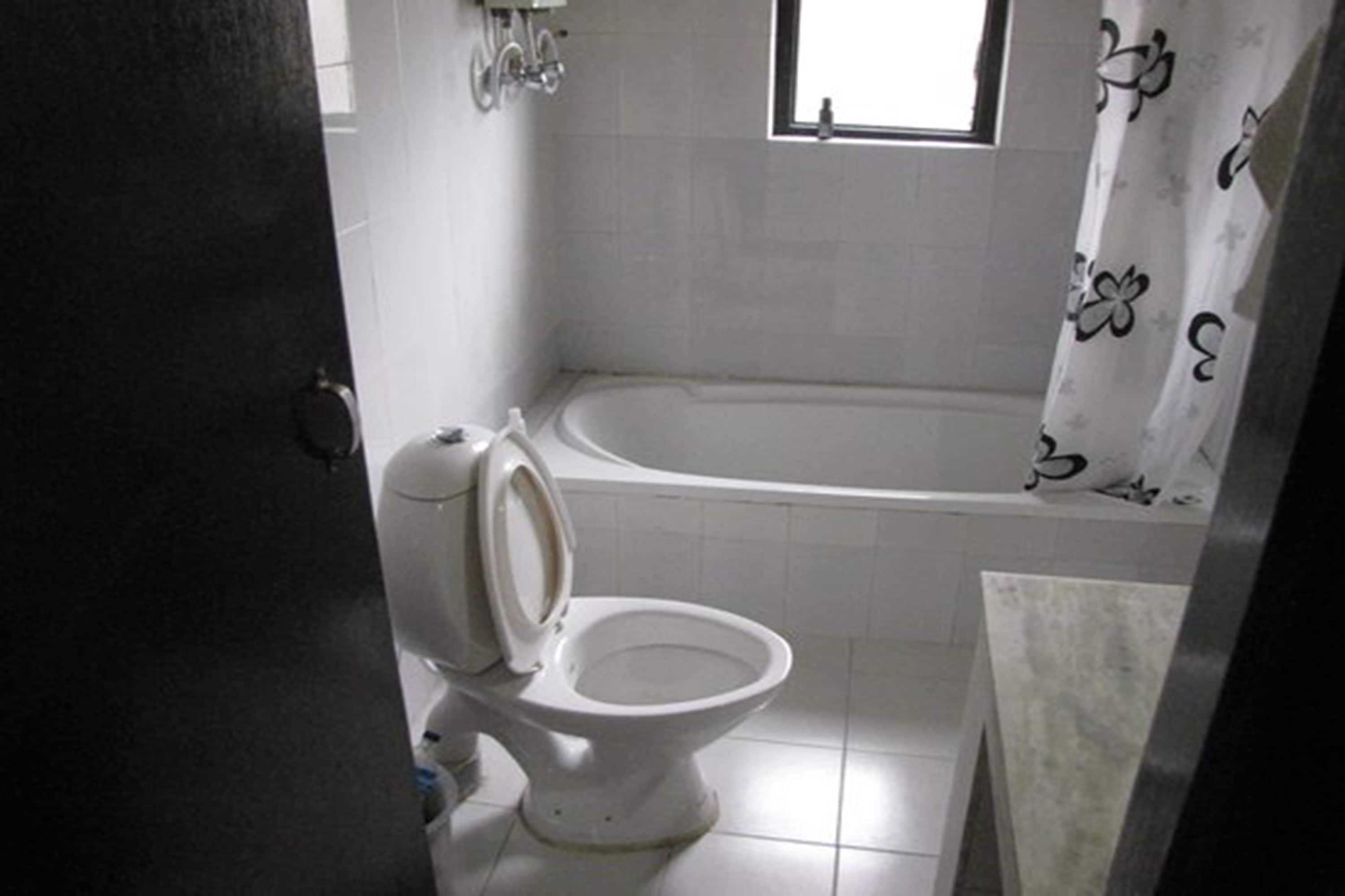 A bathroom with a toilet, a bathtub, and a window.