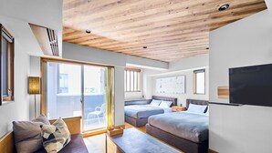Una habitación de hotel moderna con techo de madera, una cama grande, un sofá, un banco y un televisor.