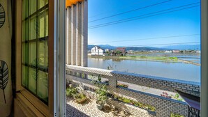 A view from a balcony with a river, buildings, and mountains in the distance. - Real Fun Homestay (Dongshan)