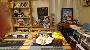 A dining area with a table set for two, featuring a plate of sandwiches, a glass of water, and a yellow teapot. - Real Fun Homestay (Dongshan)