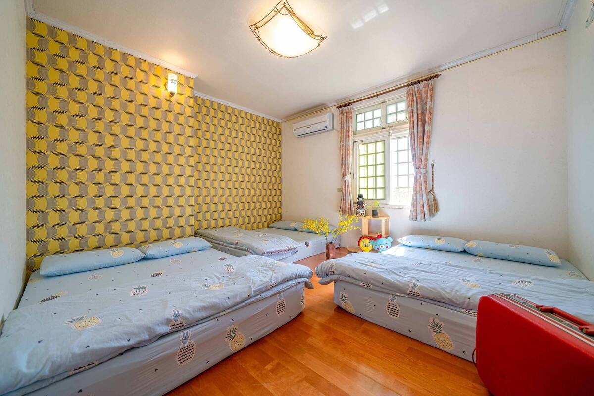 A room with two beds, a red suitcase, and a wall with a geometric pattern.