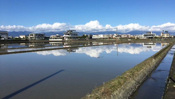A serene landscape with a clear sky, calm water reflecting buildings, and distant mountains. - Real Fun Homestay (Dongshan)