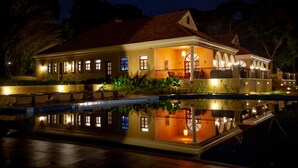 Una casa ampia e luminosa con una piscina di fronte, con diverse finestre e un balcone.