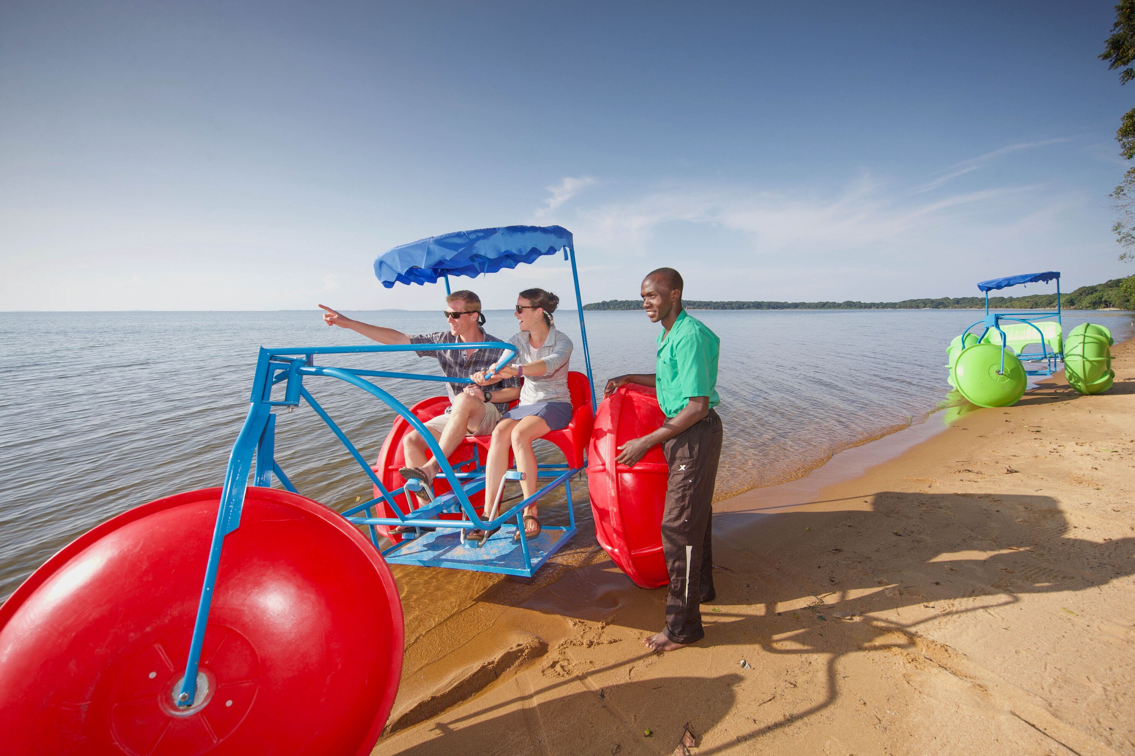 Une attraction avec une grande roue aquatique sur une plage, offrant une vue dégagée sur l’eau et le rivage au loin.