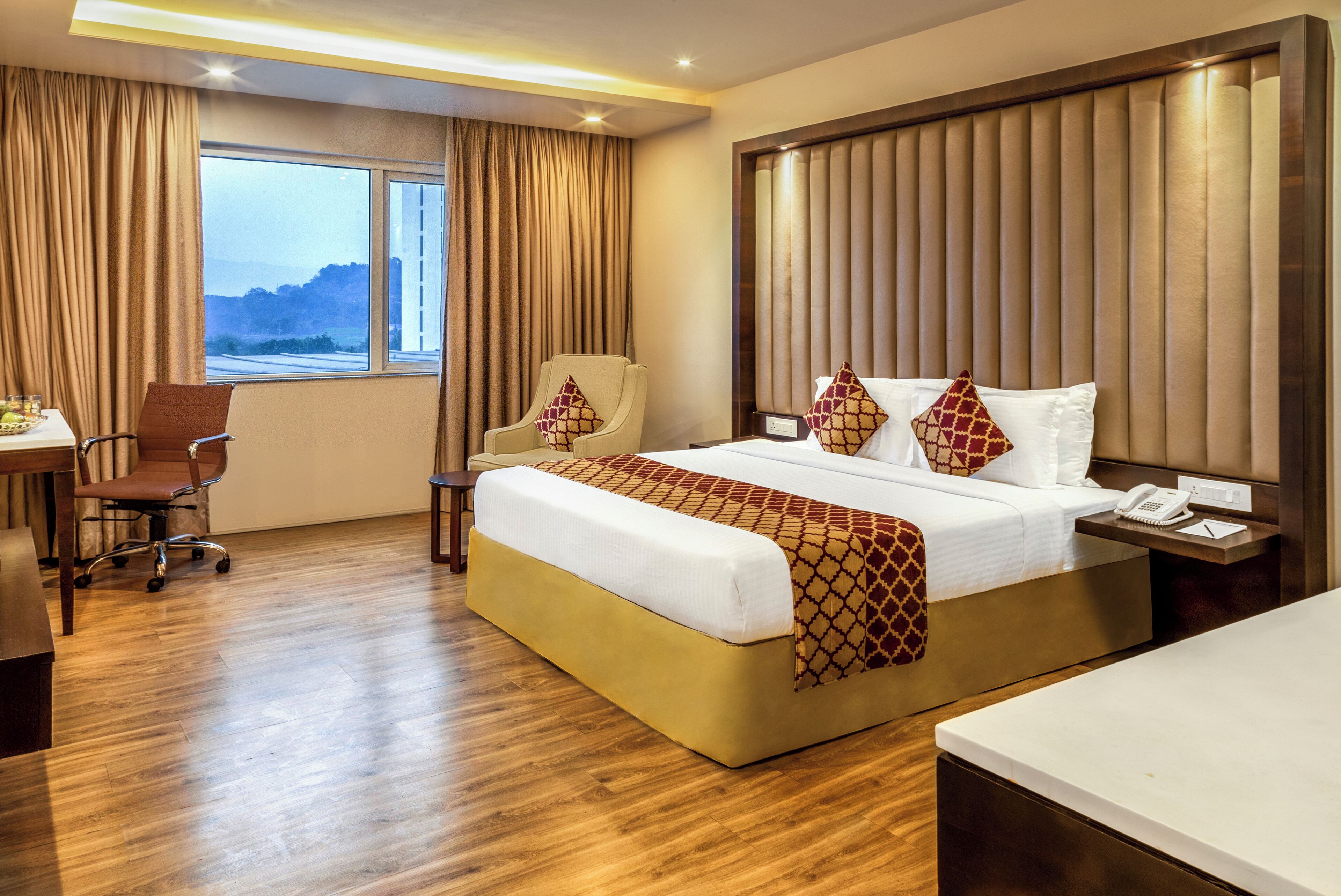 Hotelkamer met een groot bed, een bureau, een stoel en uitzicht op de omgeving.