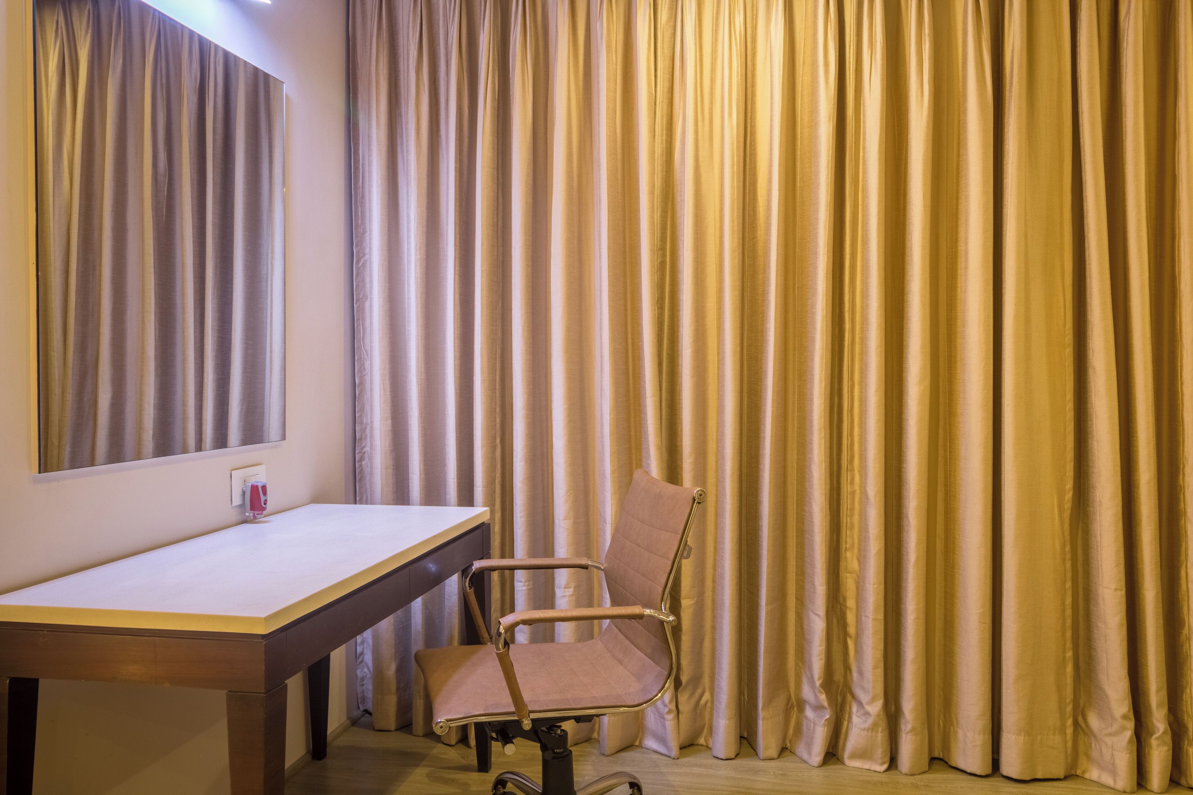 A room with a desk, chair, and curtains.